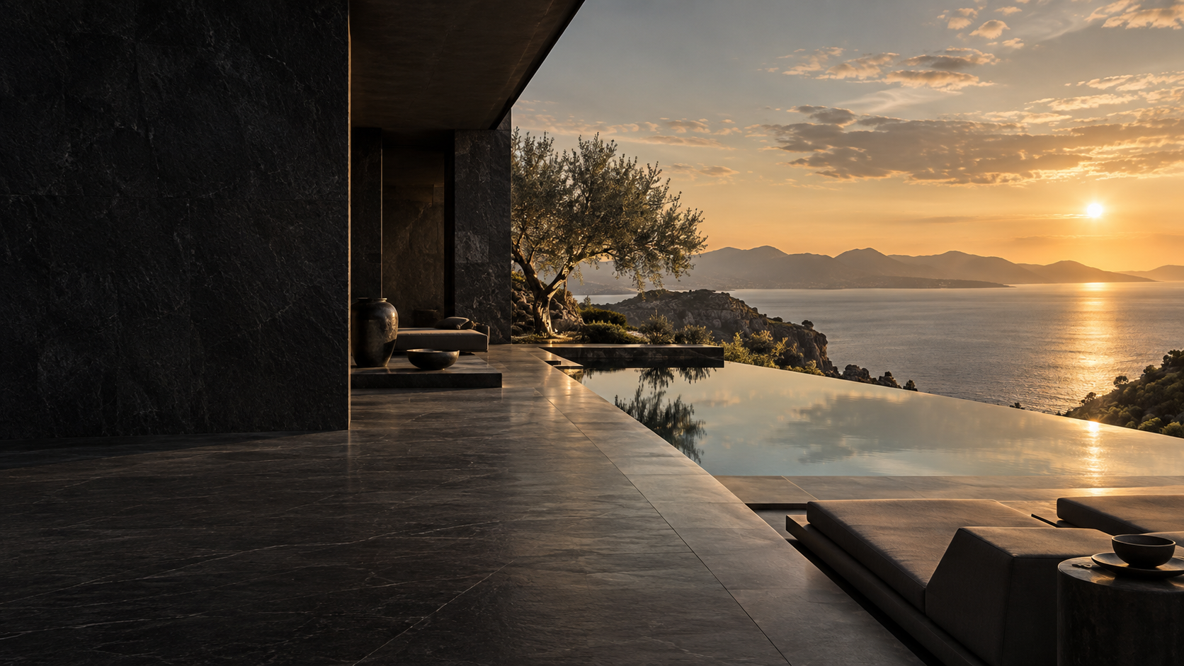 A tranquil stone terrace and infinity pool overlooking a mountain-lined coastal bay at golden hour